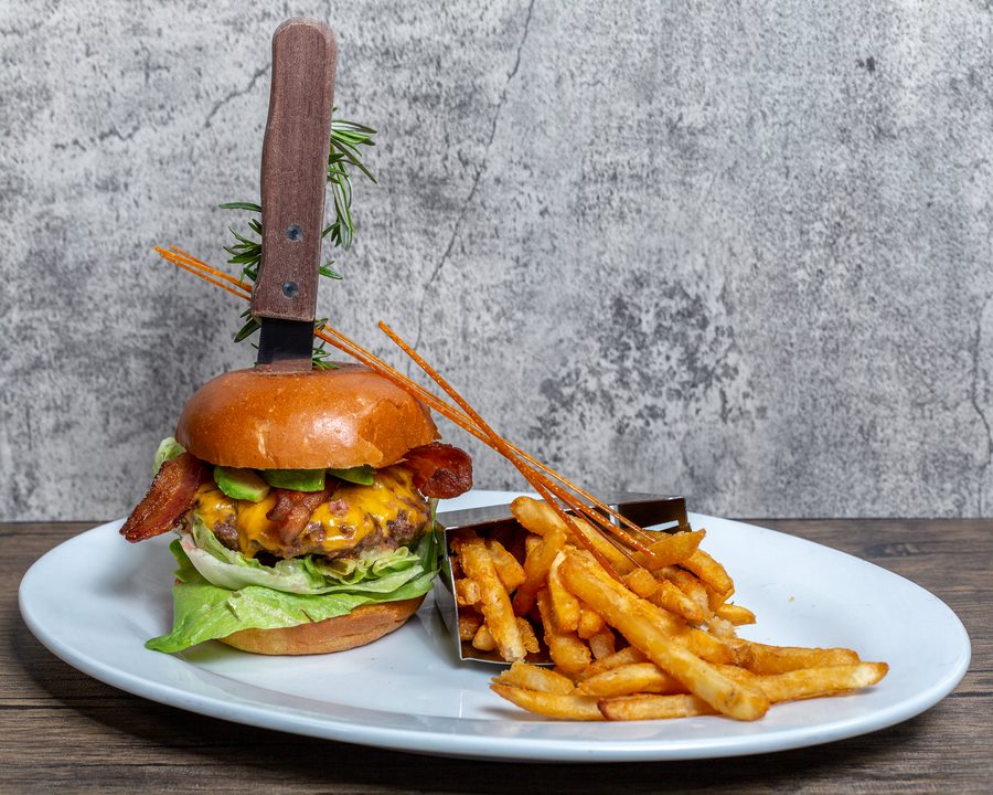 Gourmet burger with bacon, egg, and fresh lettuce served with salad at Hash House A Go Go in Mohegan Sun—comfort food meets creative presentation.
