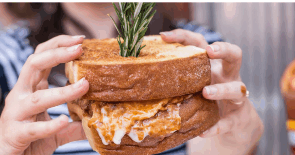 A guest enjoying a massive, sauce-filled Kokomo sandwich at Hash House A Go Go—an unforgettable dining experience in every bite.