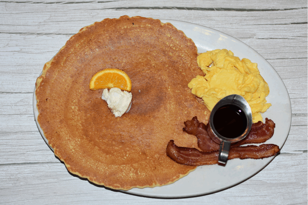 Oversized Hash House A Go Go pancake with scrambled eggs, bacon, syrup, and butter at Mohegan Sun.